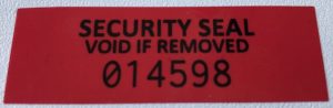 Red total transfer tamper evident label with black text and serial number