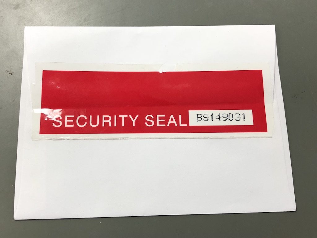 Paper envelope sealed with a red security seal tamper evident label